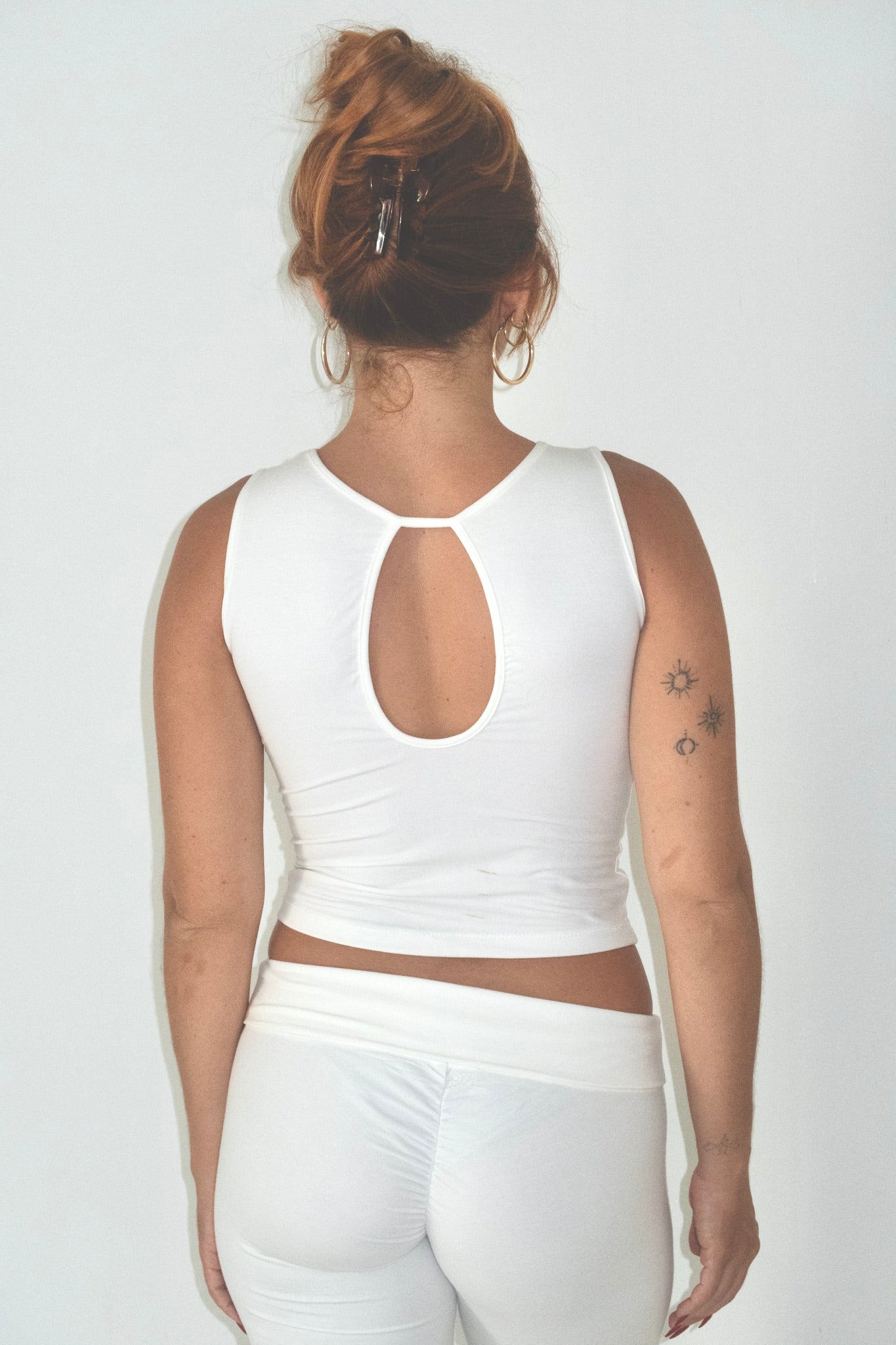Person wearing a white sleeveless top and pants on a plain background